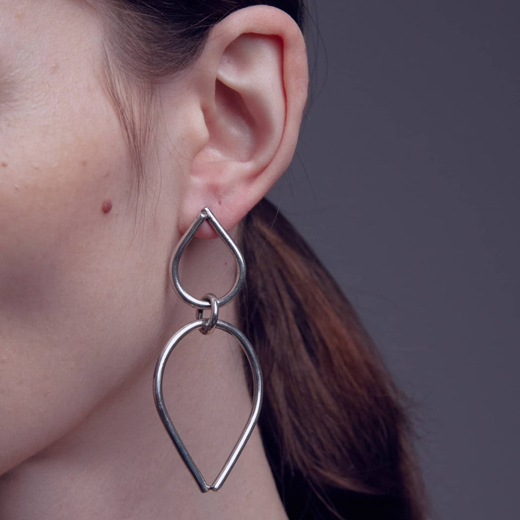 chaotic bond earrings in silver, worn on ear in close-up, INNAN Jewellery Berlin