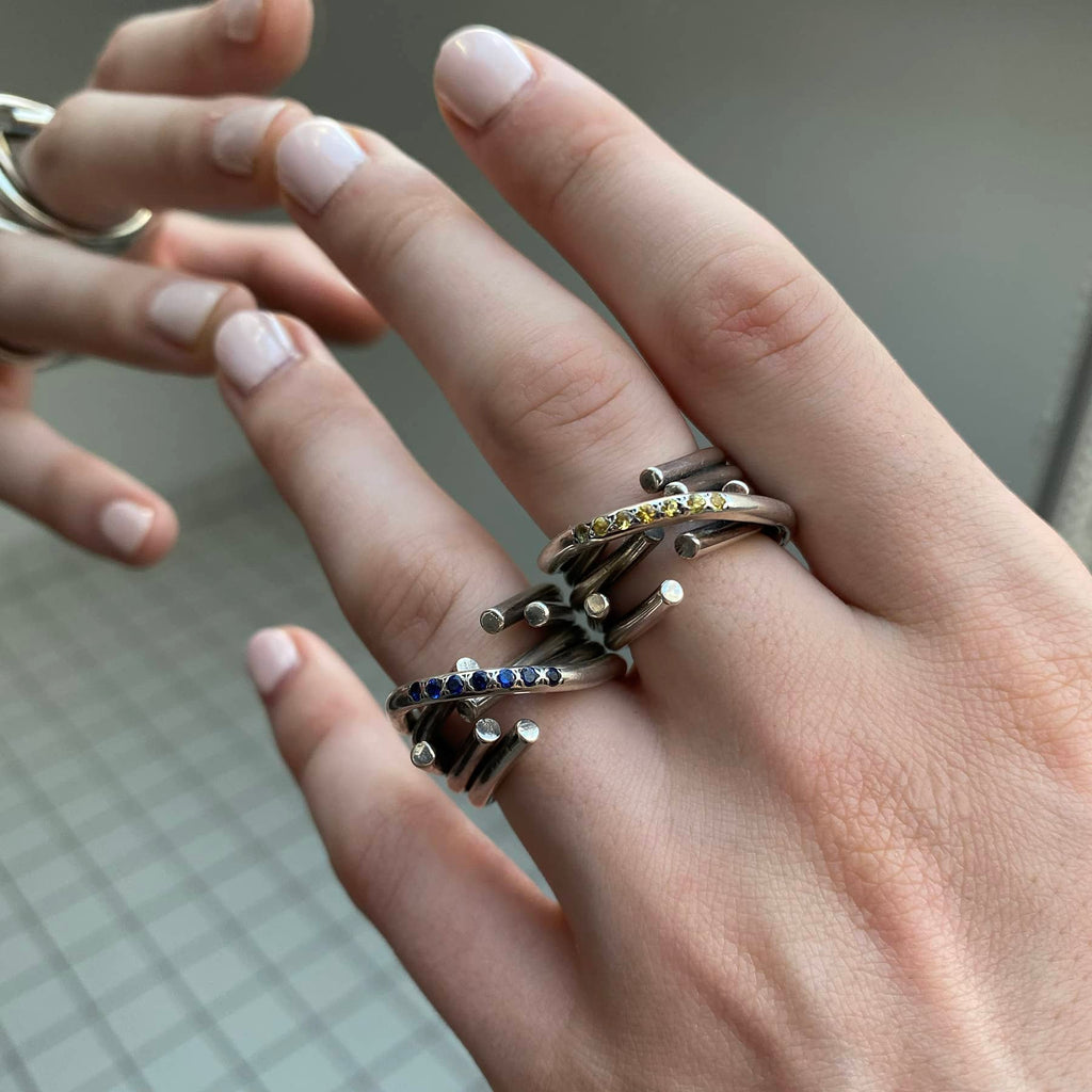 chaotic infinity ring in silver with yellow and blue sapphires, close up worn on a hand, INNAN Jewellery Berlin