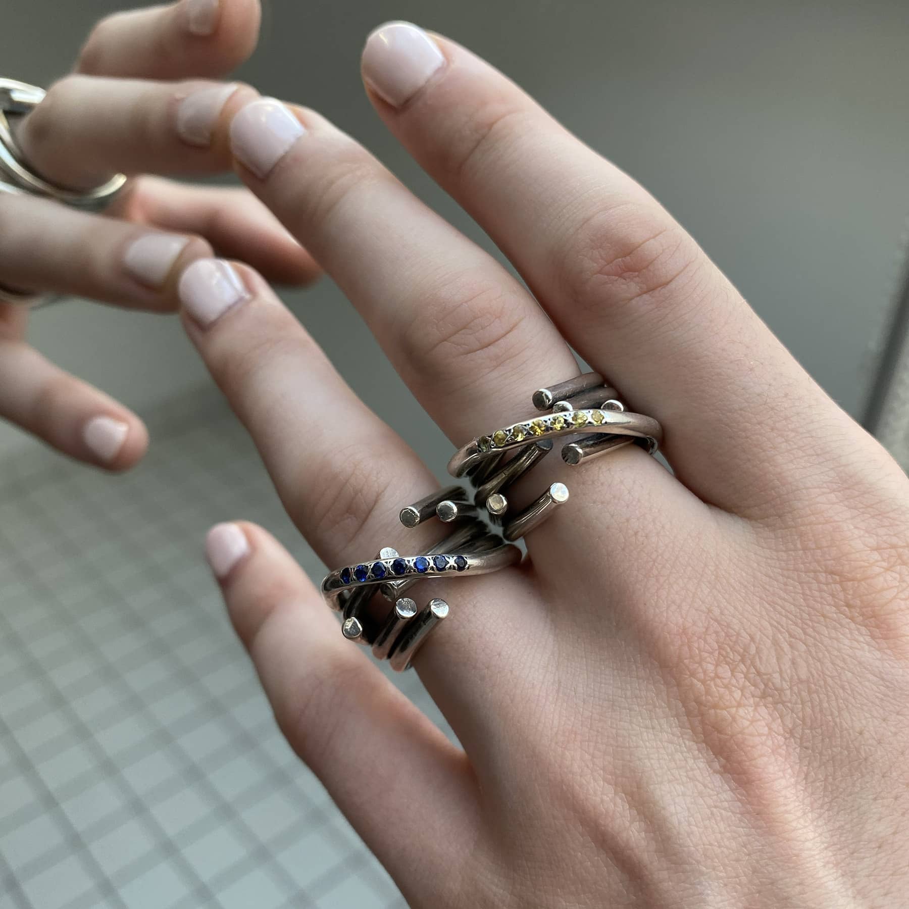 chaotic infinity ring in silver with yellow and blue sapphires, close up worn on a hand, INNAN Jewellery Berlin