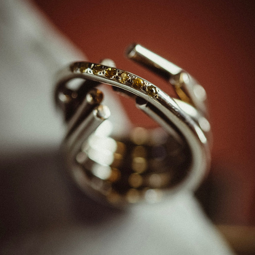 chaotic infinity ring in silver with yellow sapphires, product image close up with artistic background, INNAN Jewellery Berlin