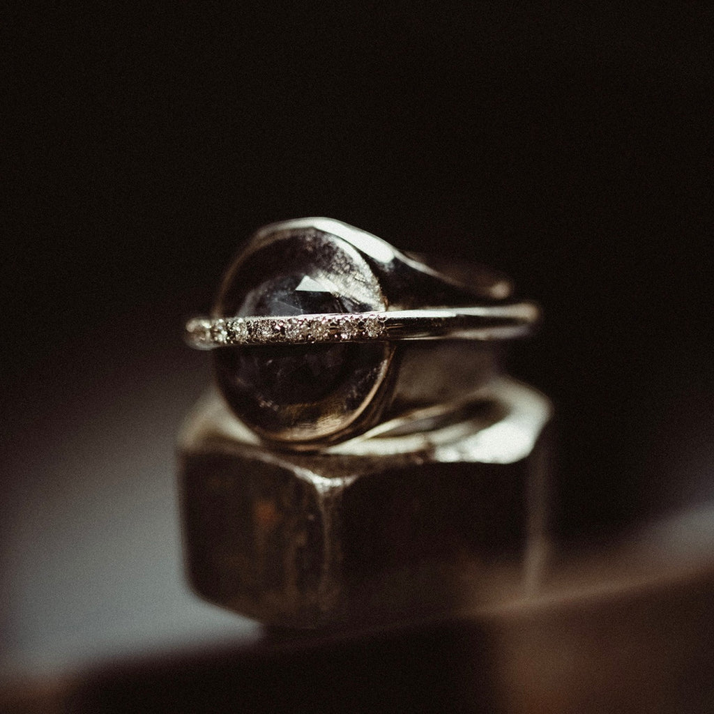 chaotic signet ring in 18 ct white gold with 2.52 ct dark indigo diamond and 9 champagne diamonds, product image with artistic background, INNAN Jewellery Berlin