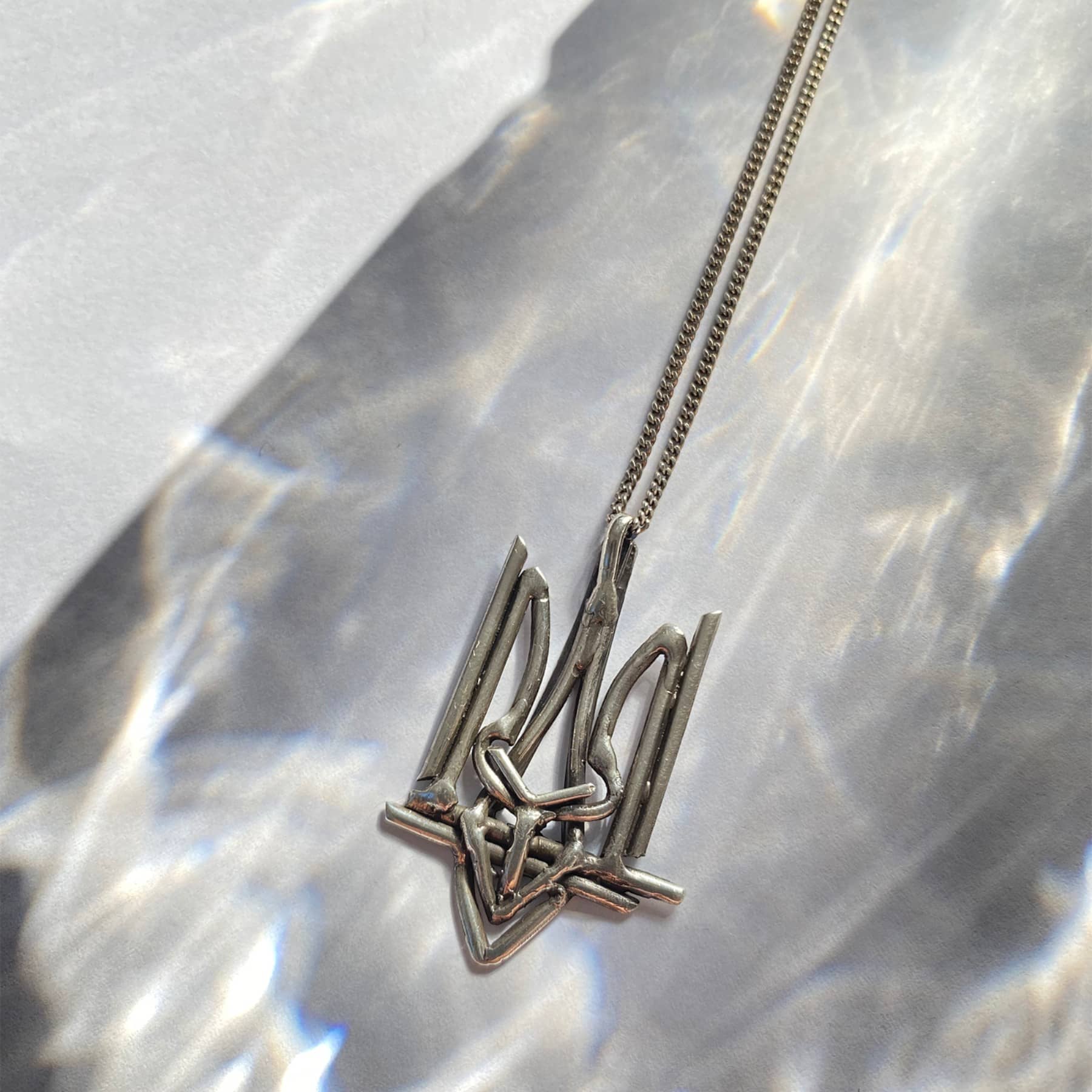 Ukrainian Trident (Tryzub) pendant necklace in silver, product image on artistic background, INNAN Jewellery Berlin
