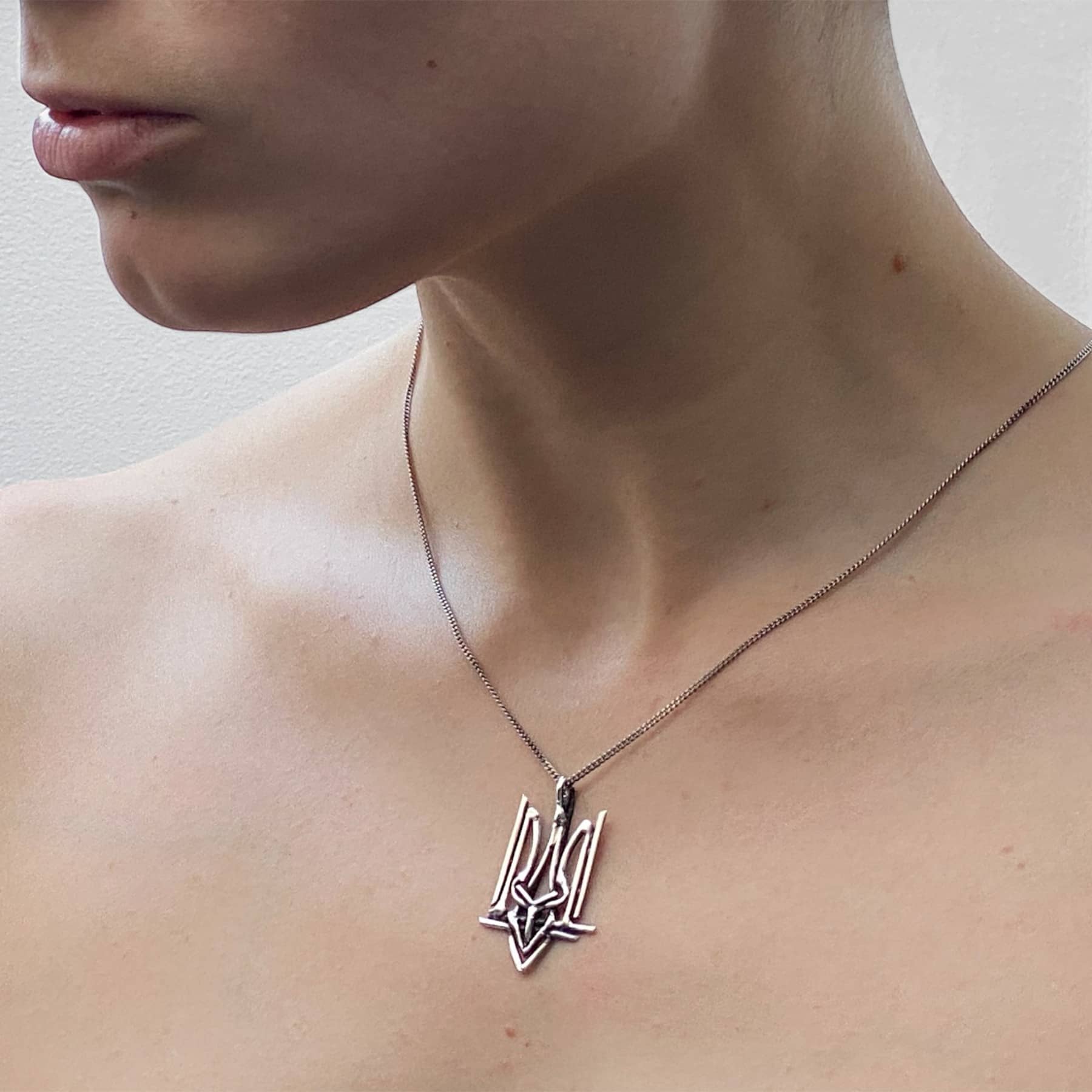 Ukrainian Trident (Tryzub) pendant necklace in silver, worn on neck, INNAN Jewellery Berlin