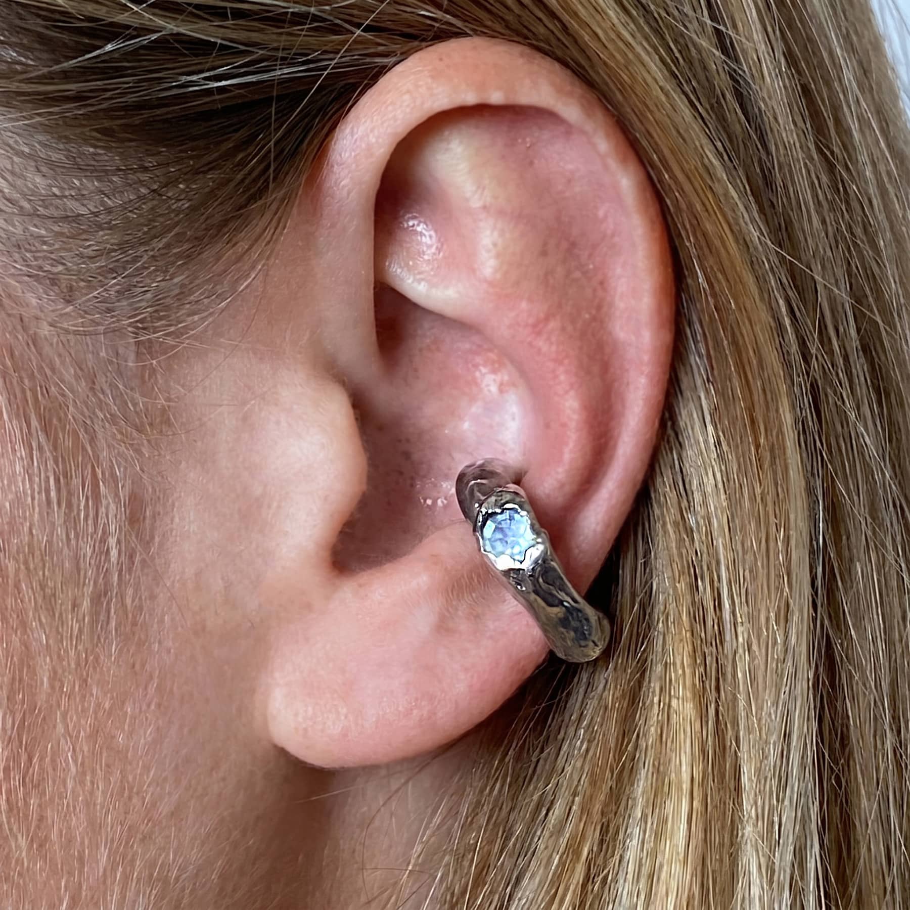 silver Askja ear cuff with blue chalcedony, worn on ear in close-up, INNAN Jewellery Berlin