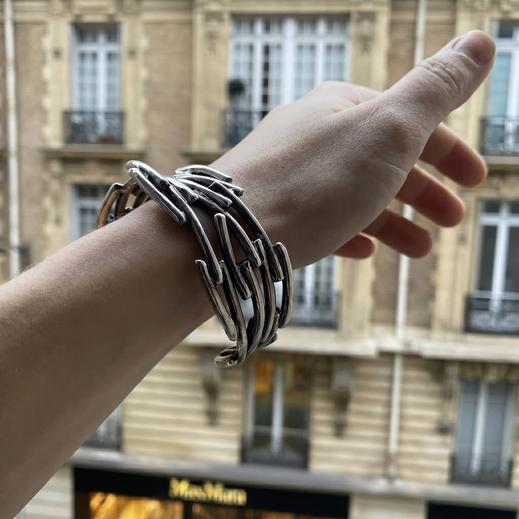 flow bracelet in silver, a close up worn on the hand with the view of a parisian street, INNAN Jewellery Berlin