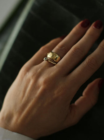 Erato I engagement ring with a 0.26 ct grey diamond paired with Lada wedding ring in 18 ct yellow gold on a model’s hand by Innan Jewellery